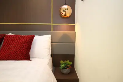 a bed with a red pillow and a potted plant at Makati - Chino Roces Trevi Towers in Manila