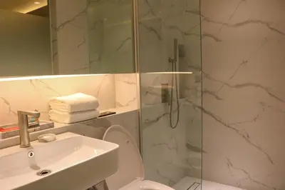 a bathroom with a shower and a toilet and a sink at Red Hotel Cubao, Quezon City in Manila