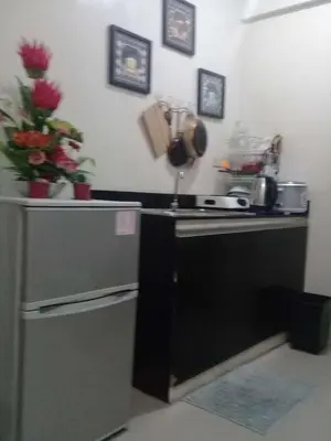 a kitchen with a stove and a sink with flowers at EKONUMI ROOMS at Moonwalk Paranaque in Manila