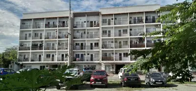 a large white building with cars parked in front of it at EKONUMI ROOMS at Moonwalk Paranaque in Manila