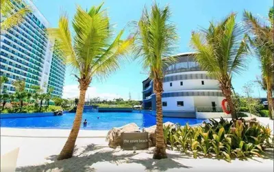 a pool with palm trees in front of a building at Azure Staycation Near Airport in Manila