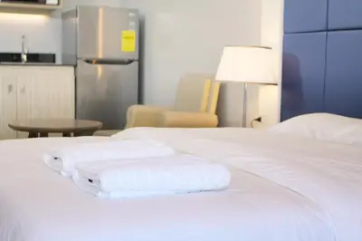 a white bed with towels on top of it at Malate Bayview Mansion city view in Manila