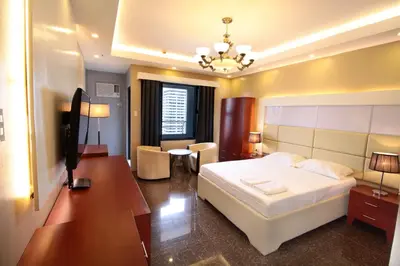 a bedroom with a white bed and a desk and a room at Malate Bayview Mansion city view in Manila
