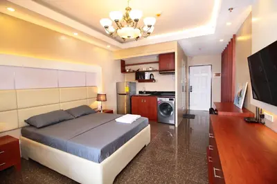 a bedroom with a large bed and a kitchen at Malate Bayview Mansion city view in Manila