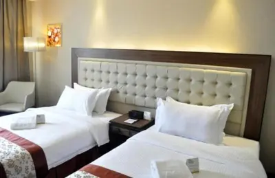 a hotel room with two beds and a chair at ACE Hotel and Suites in Manila