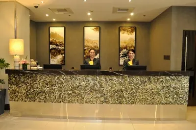 a lobby with three people sitting at a reception counter at ACE Hotel and Suites in Manila