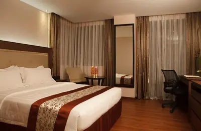 a hotel room with a large bed and a desk at ACE Hotel and Suites in Manila