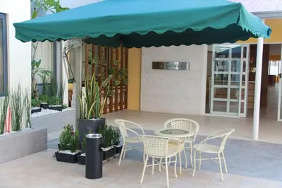 a table and chairs under a blue umbrella at ACE Hotel and Suites in Manila