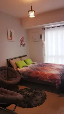 a bedroom with a bed and a chair and a window at Studio Fully Furnished in Manila