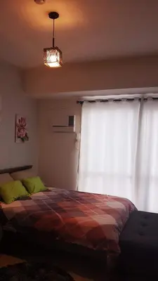 a bedroom with a bed in front of a window at Studio Fully Furnished in Manila