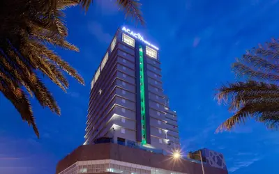 a tall building with a green sign on it at Acacia Hotel Manila in Manila