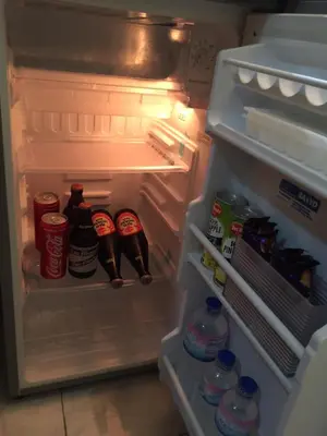 an open refrigerator filled with drinks and soda at Las Pinas Serviced Apartment in Manila