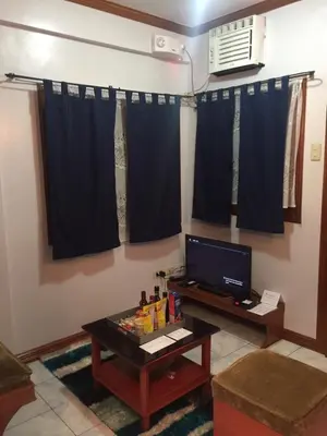 a living room with a table and a tv at Las Pinas Serviced Apartment in Manila