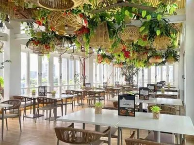 a dining room with tables and chairs and plants at Selah Pods Hotel Manila in Manila