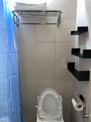 a bathroom with a toilet with a blue shower curtain at A Home with a view, 1 Bdrm with balcony and Netflix Access in Manila
