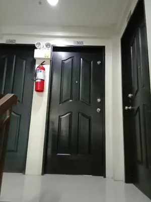 two black doors with a fire extinguisher on them at Jen's Paranaque City Apartment in Manila