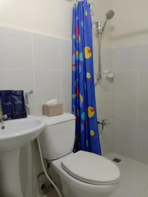 a bathroom with a toilet and a shower curtain at Jen's Paranaque City Apartment in Manila