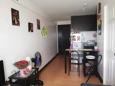 a kitchen with black cabinets and a table with chairs at The Escape Pad 1 by Sharon May in Manila