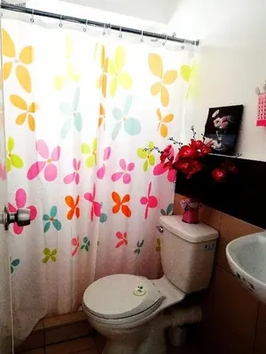 a bathroom with a toilet and a shower curtain with flowers at The Escape Pad 1 by Sharon May in Manila