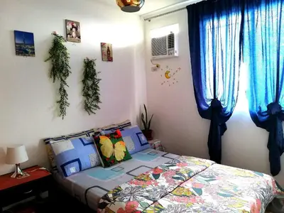 a bedroom with a bed and blue curtains at The Escape Pad 1 by Sharon May in Manila