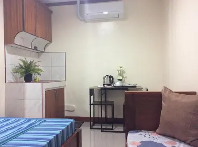 a room with a bed and a kitchen with a table at Bing's Place in Manila