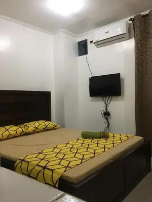 a bedroom with a bed and a tv on the wall at Bing's Place in Manila