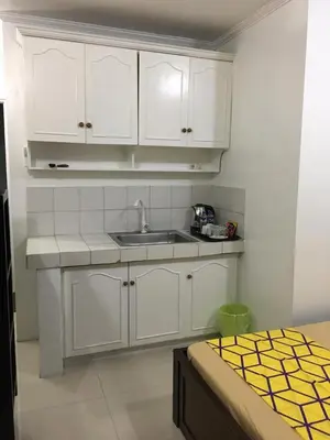 a kitchen with white cabinets and a sink at Bing's Place in Manila