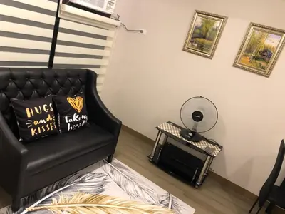 a bedroom with a black couch and a mirror at The Sentinel Residences Suite in Manila