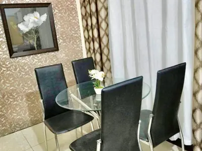 a dining room with a glass table and black chairs at Super Cute Hampton Suites in Imus