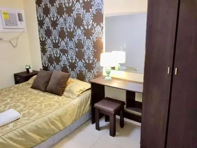 a bedroom with a bed and a desk with a lamp at Super Cute Hampton Suites in Imus