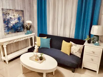 a living room with a blue couch and a table at Super Cute Hampton Suites in Imus