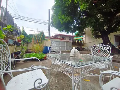 a table and chairs in a yard with a tree at Bed and Brewhouse Sucat in Manila
