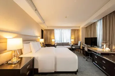 a hotel room with a large white bed and a desk at Quest Plus Filinvest City Manila in Manila
