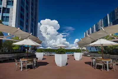 a patio with tables and chairs with umbrellas at Quest Plus Filinvest City Manila in Manila