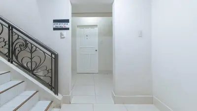 a white hallway with stairs and a white door at RedDoorz at Samat Mandaluyong in Manila
