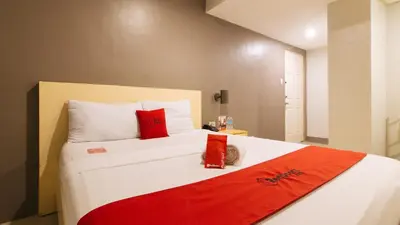 a bedroom with a large white bed with red pillows at RedDoorz at Samat Mandaluyong in Manila