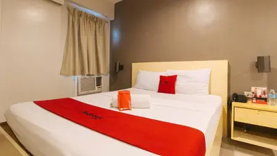 a bedroom with a large white bed with red pillows at RedDoorz at Samat Mandaluyong in Manila