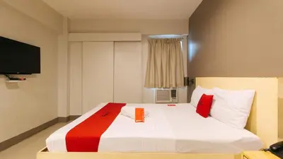 a bedroom with a large white bed with red pillows at RedDoorz at Samat Mandaluyong in Manila