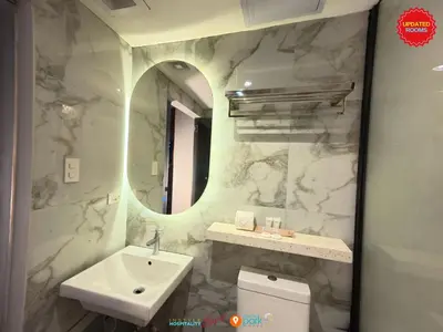 a bathroom with a sink and a toilet and a mirror at Citizen Hotel in Manila