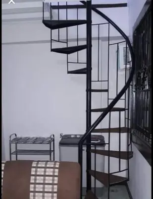 a black spiral staircase in a room with a table at Estien's cozy home in Malagasang Primero