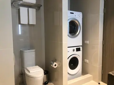 a bathroom with a toilet and a washer and dryer at Seda Residences Makati in Manila