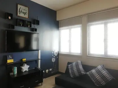 a living room with a couch and a flat screen tv at Affordable Cozy Pad in Salcedo Village Makati in Manila