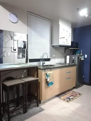a kitchen with a sink and a counter with stools at Affordable Cozy Pad in Salcedo Village Makati in Manila