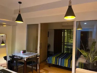 a room with a table and chairs and a bedroom at Great 1BR Aqua Livingstone with Netflix, Pool & Gym in Manila