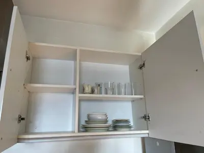 a kitchen with white cabinets with plates and dishes at Great 1BR Aqua Livingstone with Netflix, Pool & Gym in Manila