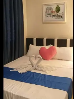 a bed with two heart shaped pillows on it at Jen's Paranaque City Apartment in Manila