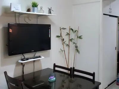 a living room with a table and a tv on a wall at Jen's Paranaque City Apartment in Manila