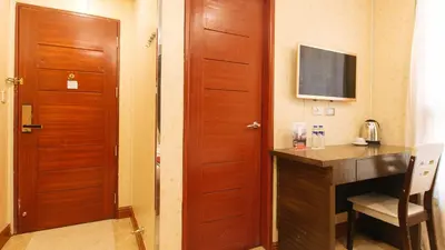 a room with a desk and a door with a television at RedDoorz Plus at Winter Benitez in Manila