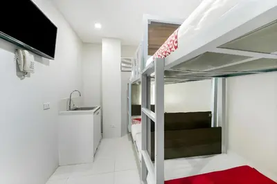 a small room with a bunk bed and a sink at OYO 152 Sangco Condotel in Manila