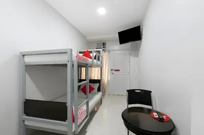 a room with a bunk bed and a desk and a table at OYO 152 Sangco Condotel in Manila